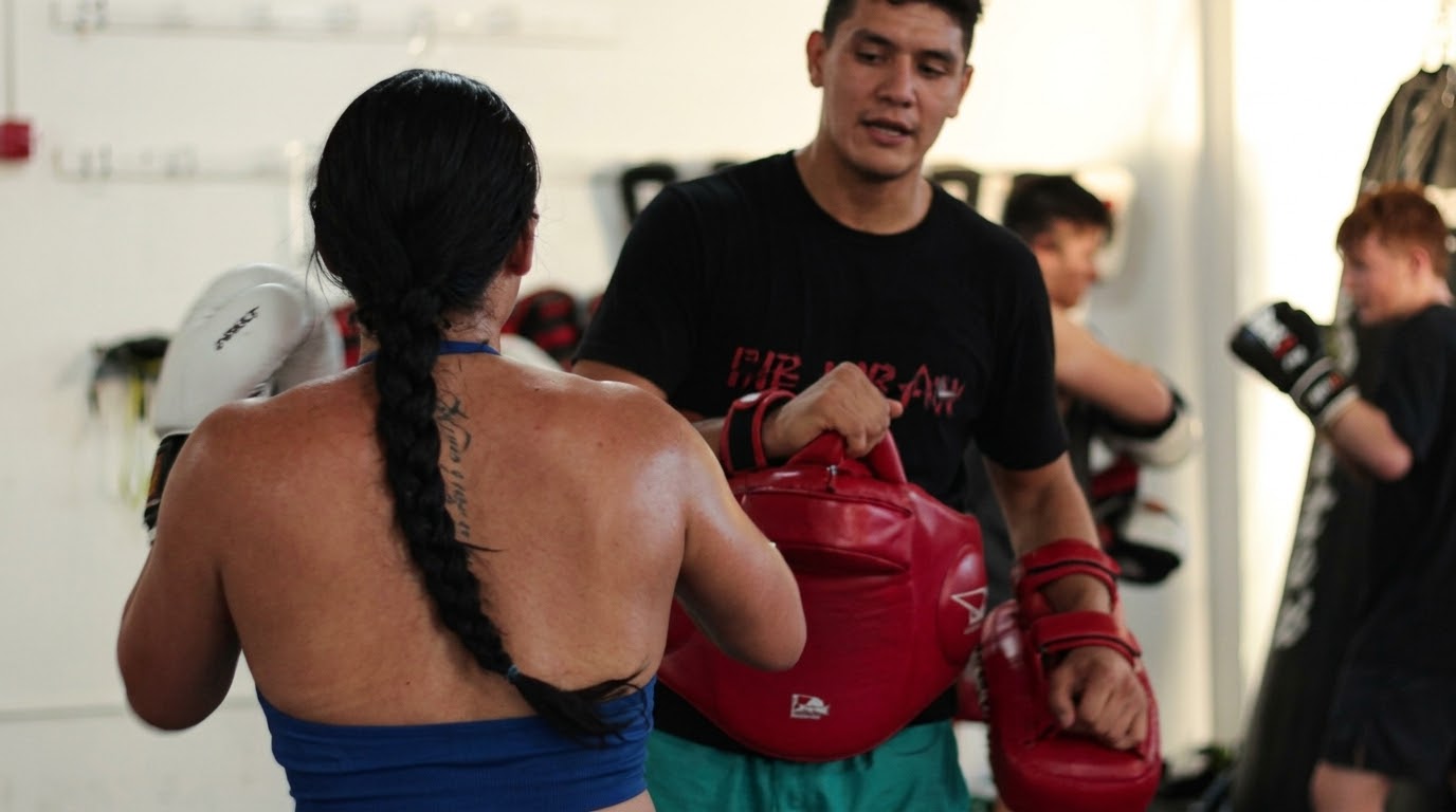 Joseph holding a belly pad and Thai pads for a client during a private session